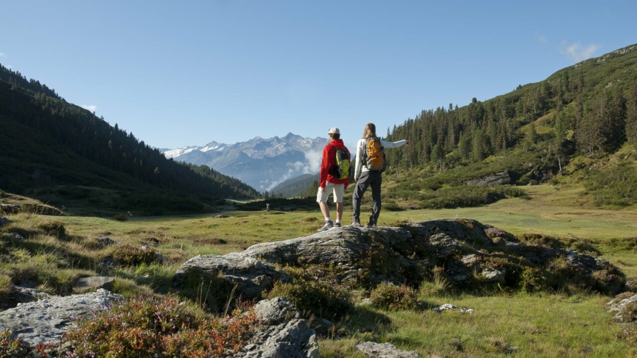 Paar steht auf Felsen und betrachtet Berge.