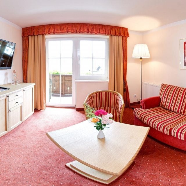 Helles Wohnzimmer mit Fernseher und Balkon