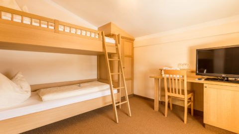 Helles Kinderzimmer mit Etagenbett und Schreibtisch.
