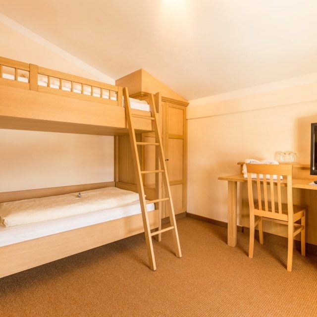 Helles Kinderzimmer mit Etagenbett und Schreibtisch.