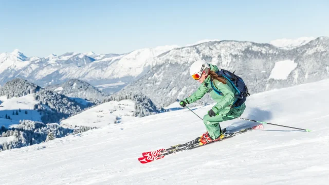 Skier navigating snowy slope with mountains in background.