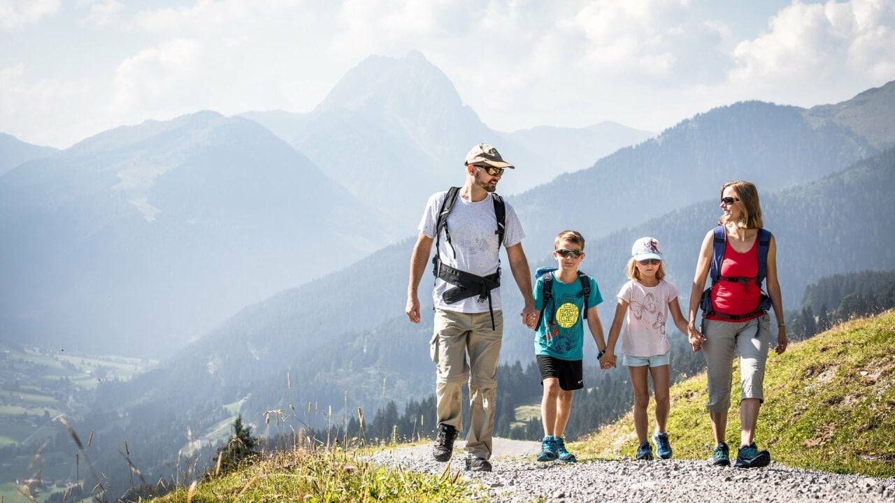 Familie wandert in den Bergen bei sonnigem Wetter.