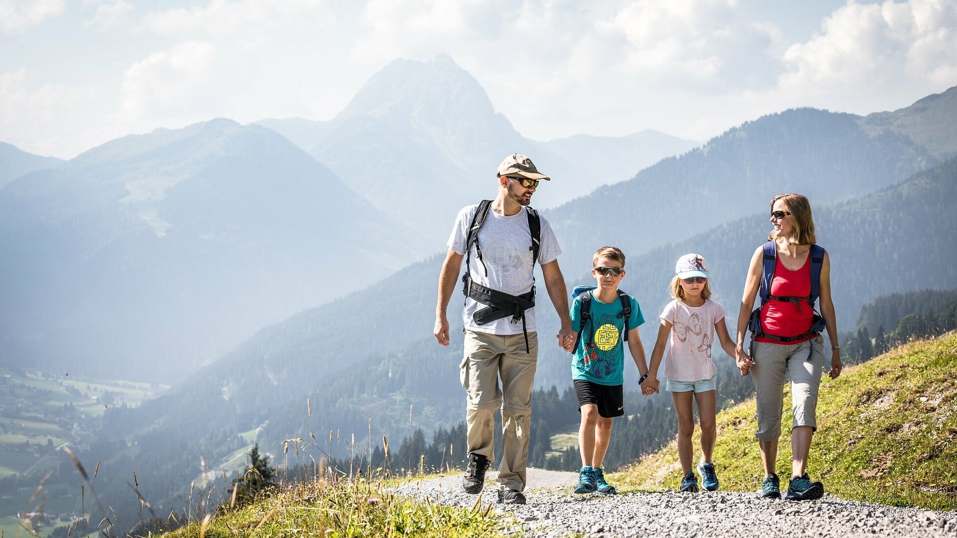 Familie wandert in den Bergen bei sonnigem Wetter.