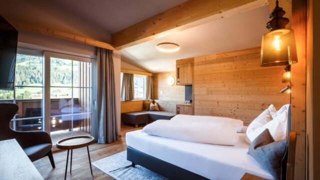 Gemütliches Hotelzimmer mit Holzdetails und Balkon.