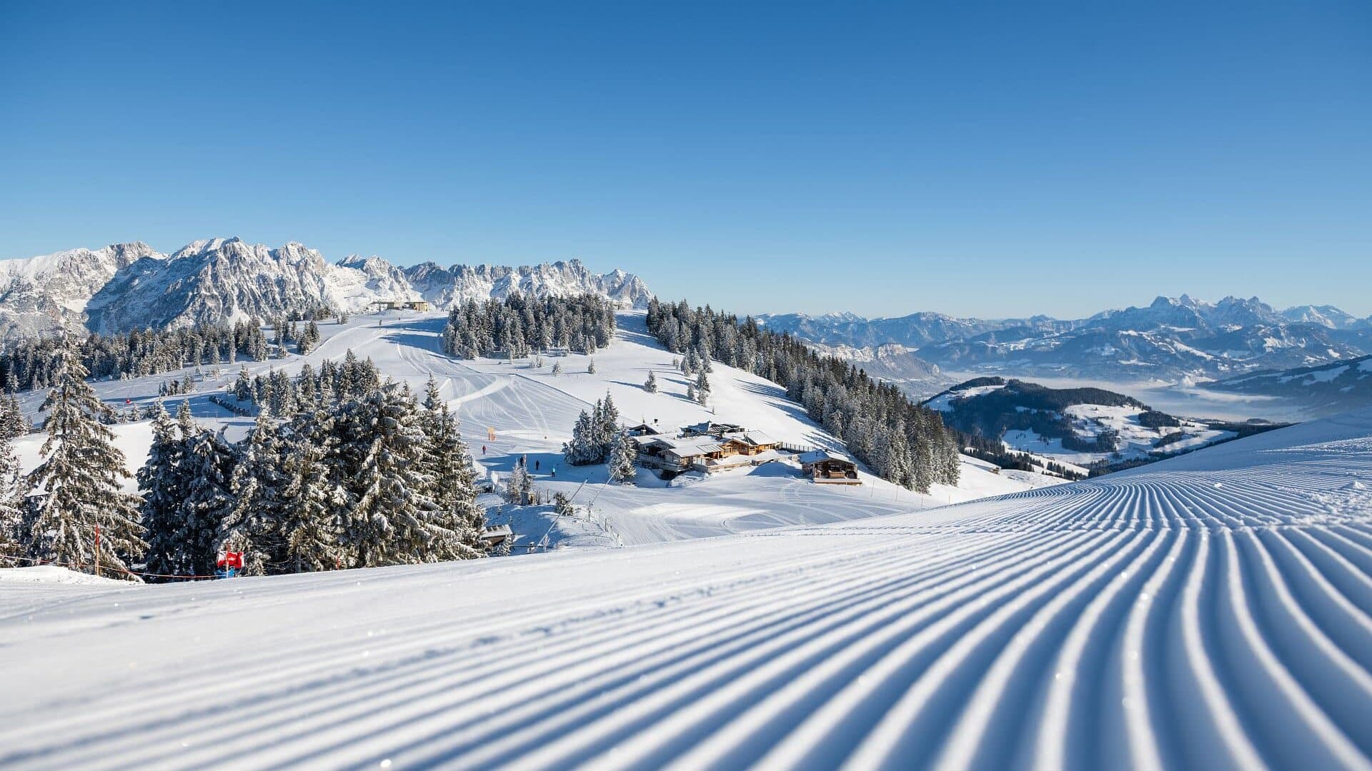 Schneebedeckte Berge und präparierte Pisten.
