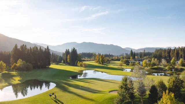 Golfplatz mit Bergen und Bäumen im Hintergrund