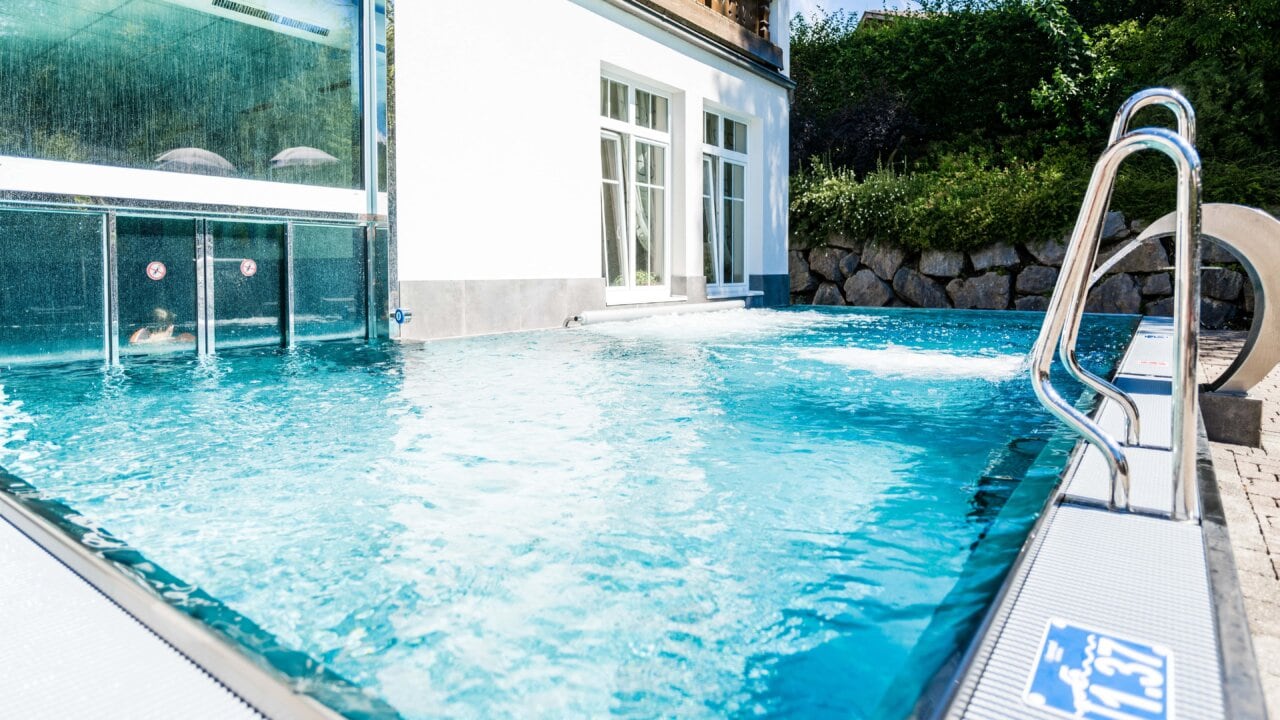 Schwimmbad mit klarem Wasser und Treppe.