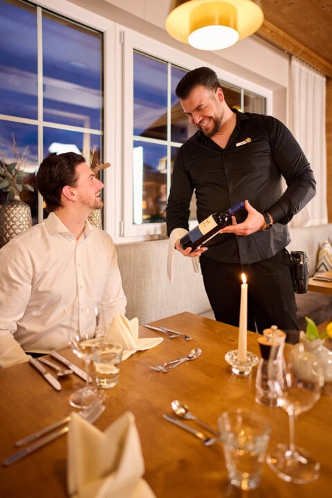 Kellner serviert Wein an Gast im Restaurant.
