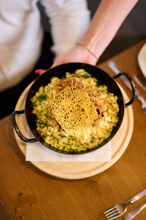 Käsespätzle mit knusprigem Topping in einer Pfanne.