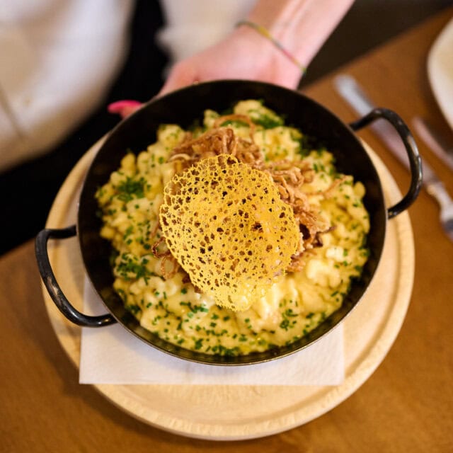 Käsespätzle mit knusprigem Topping in einer Pfanne.