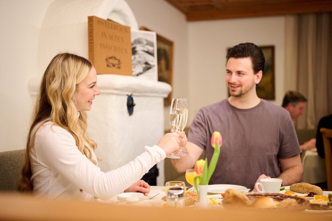 Pärchen stößt mit Gläsern an beim Frühstück