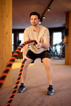 Mann trainiert mit einem Battle Rope im Fitnessstudio