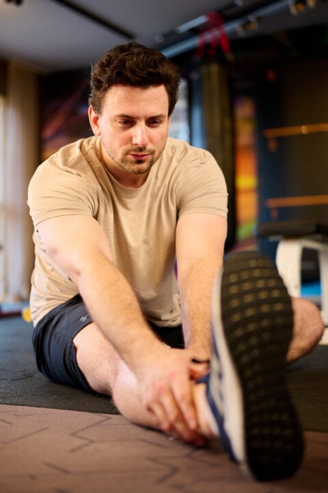 Mann macht Dehnübungen im Fitnessstudio.