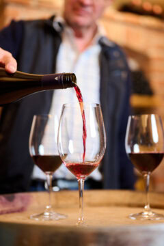 Rotwein wird in ein Weinglas ausgegossen.