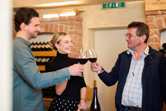 Drei Personen stoßen mit Weingläsern an.
