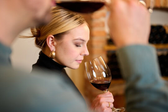 Frau riecht Wein in einem Glas.