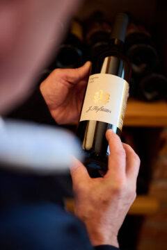 Mann hält eine Flasche Lagrein Wein.