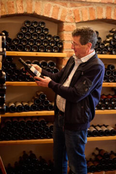 Mann betrachtet Weinflasche in Weinkeller.