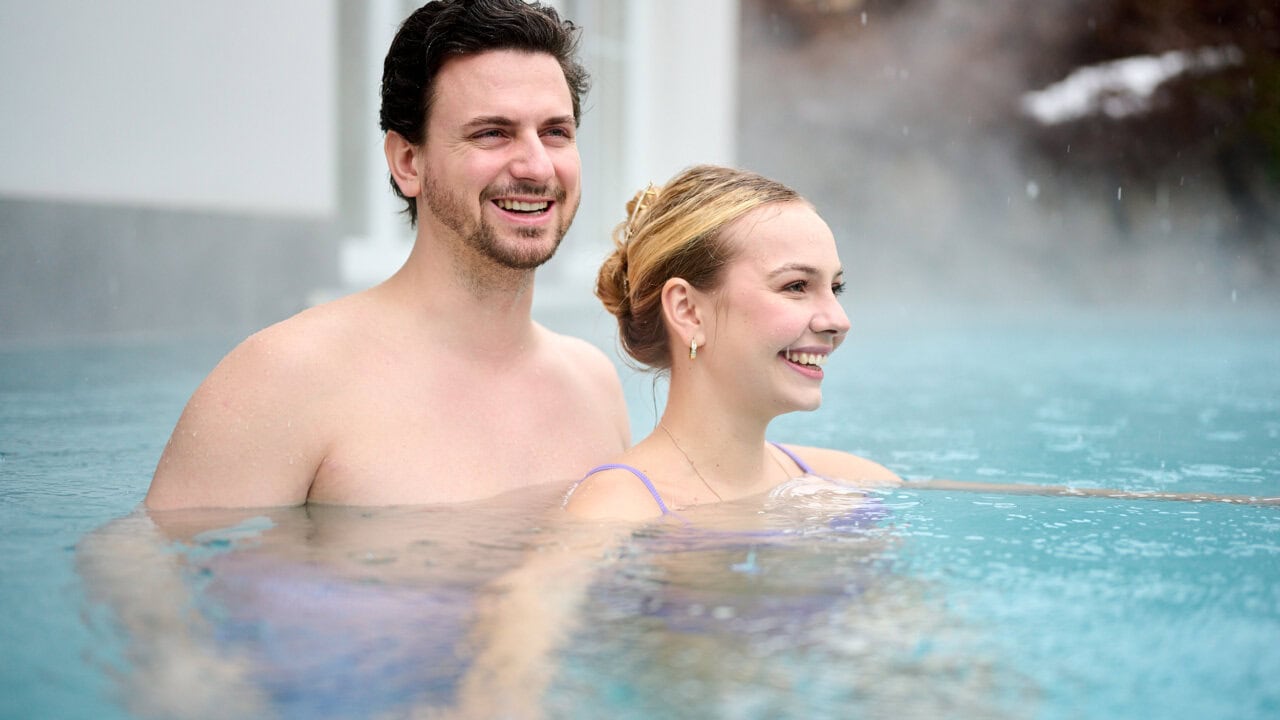 Paar im Wasser mit glücklichen Gesichtsausdrücken.