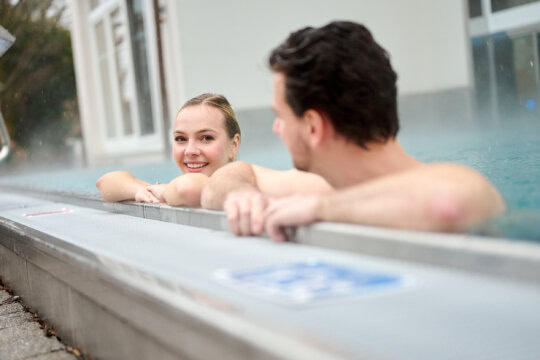Paar entspannt im Wellnessbereich im Wasser.