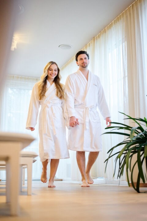 Paar in Bademänteln im Spa-Bereich.