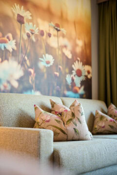 Gemütliches Sofa mit blühenden Kissen und Hintergrund