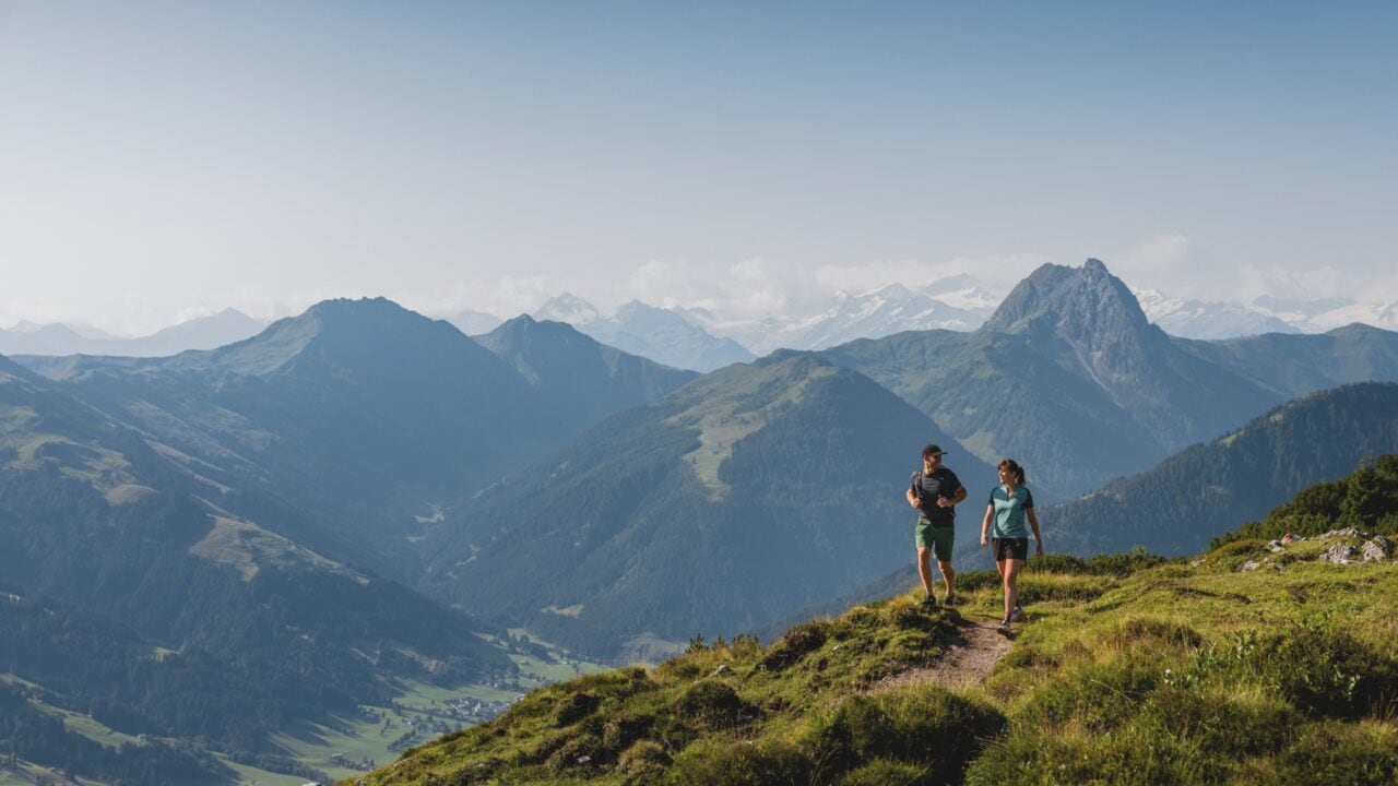 Zwei Wanderer auf einem Bergweg mit Ausblick.