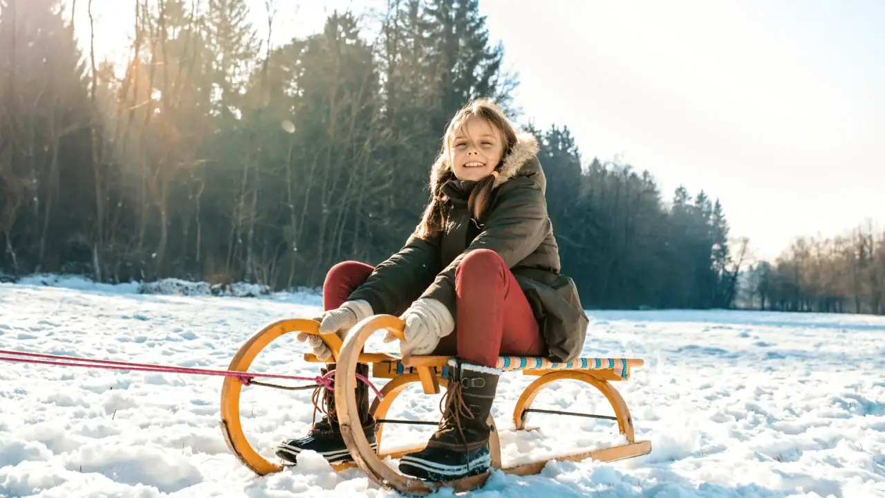 Mädchen im Schnee auf einem Schlitten