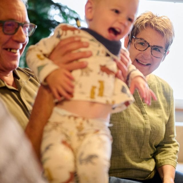 Spiele mit Großeltern und Enkelkind im Wohnzimmer.