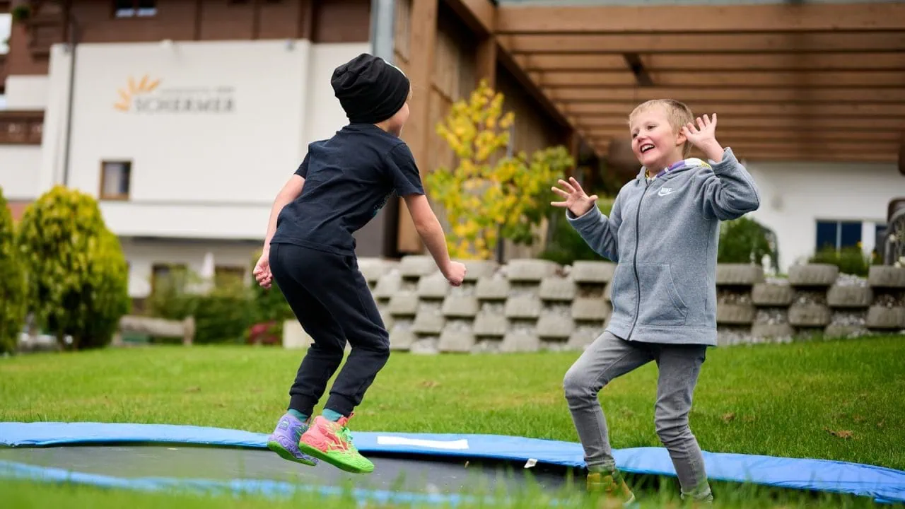 Zwei Kinder springen fröhlich auf einem Trampolin.