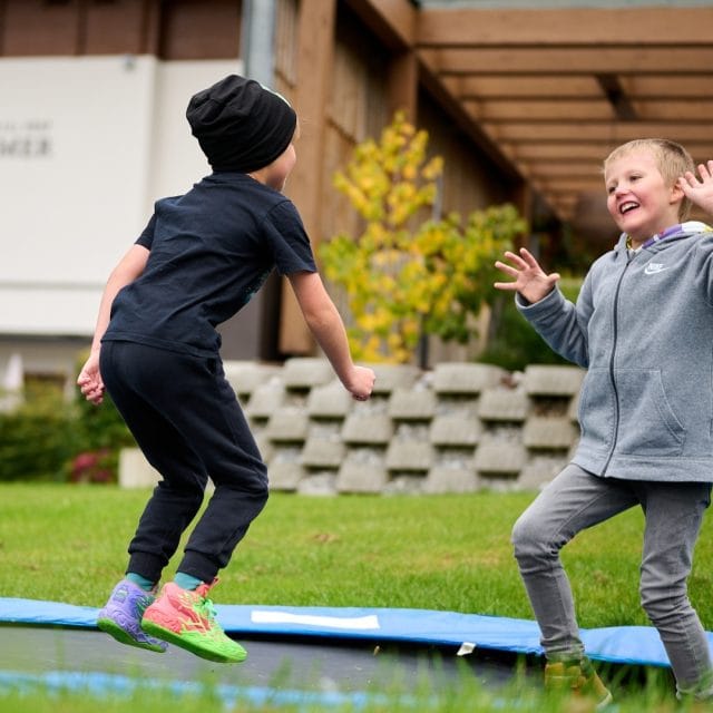 Zwei Kinder springen fröhlich auf einem Trampolin.