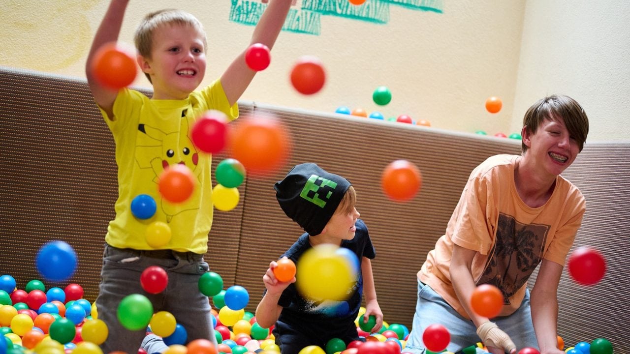 Kinder spielen mit bunten Bällen in einem Raum