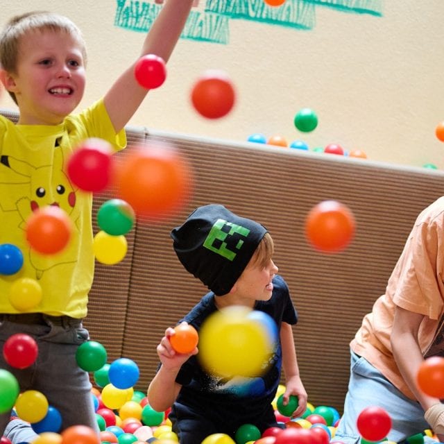 Kinder spielen mit bunten Bällen in einem Raum