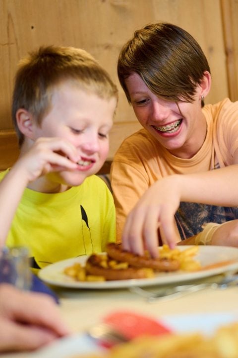 Zwei Kinder genießen ihr Essen am Tisch.