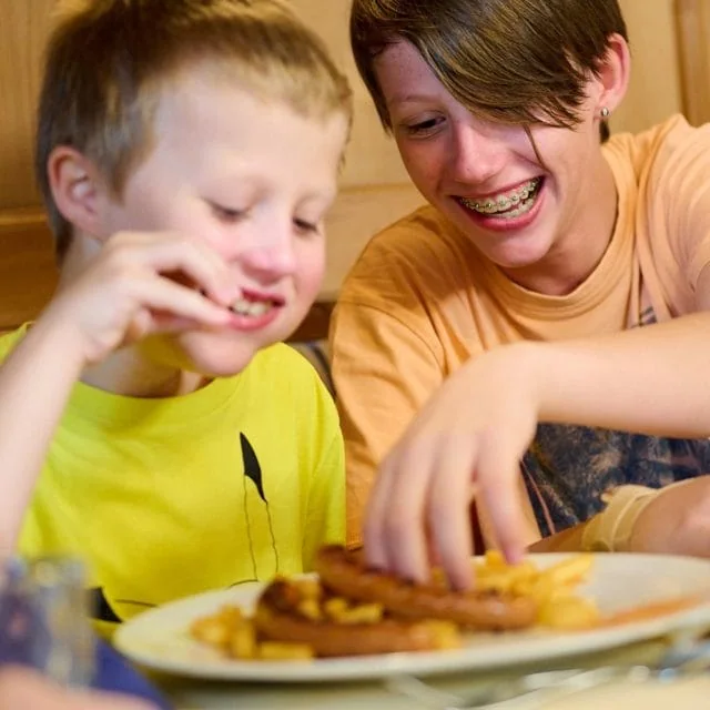 Zwei Kinder genießen ihr Essen am Tisch.