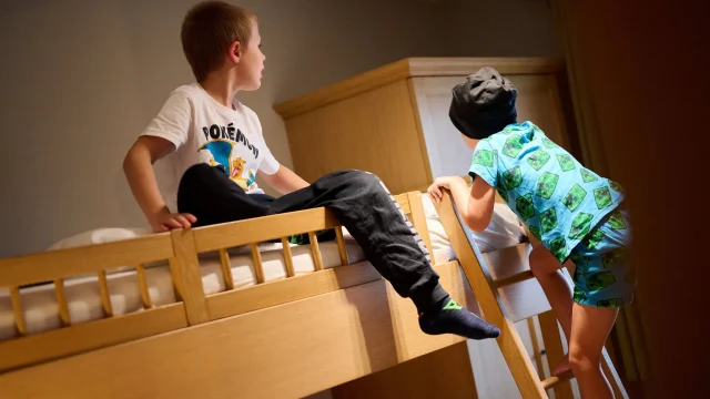 Zwei Jungen spielen gemeinsam auf einem hölzernen Etagenbett.