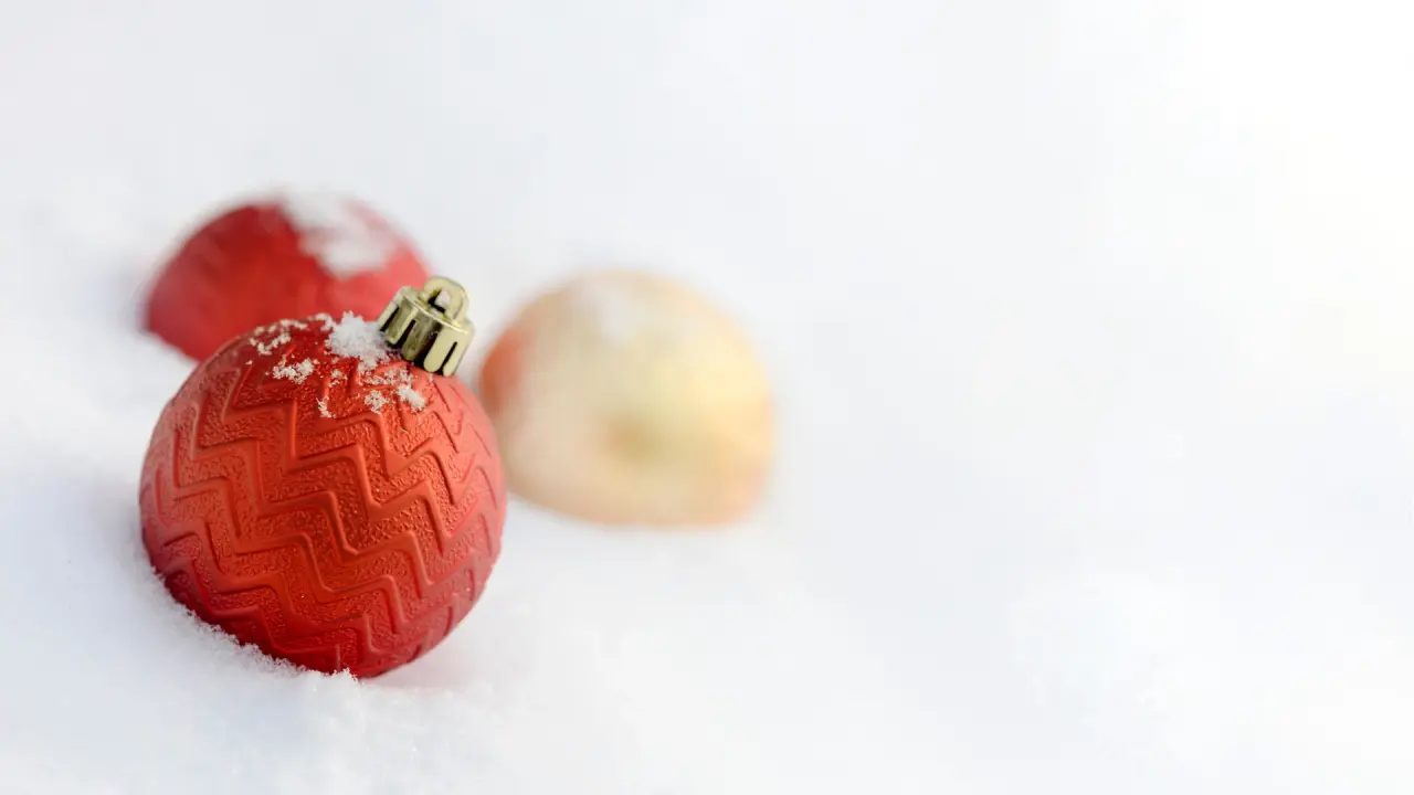 Rote Weihnachtskugel mit Muster im weißen Schnee.